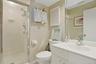 Full bath with wallpapered walls, a stall shower, and vanity