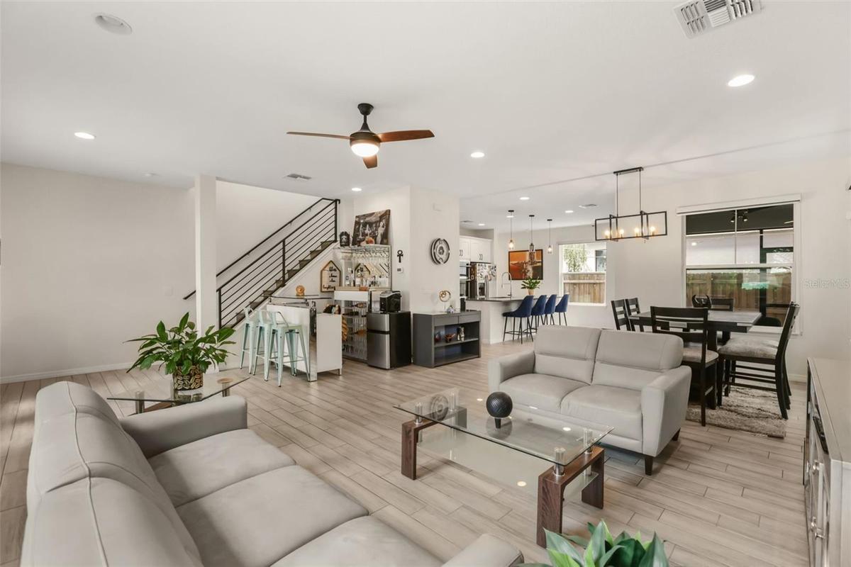 Bright open concept living room featuring high ceilings, abundant natural light, and seamless flow to the dining area and kitchen.