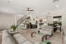 Bright open concept living room featuring high ceilings, abundant natural light, and seamless flow to the dining area and kitchen.