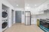 Kitchen with stainless steel appliances, white cabinets, stacked washer and clothes dryer, electric panel, and recessed lighting