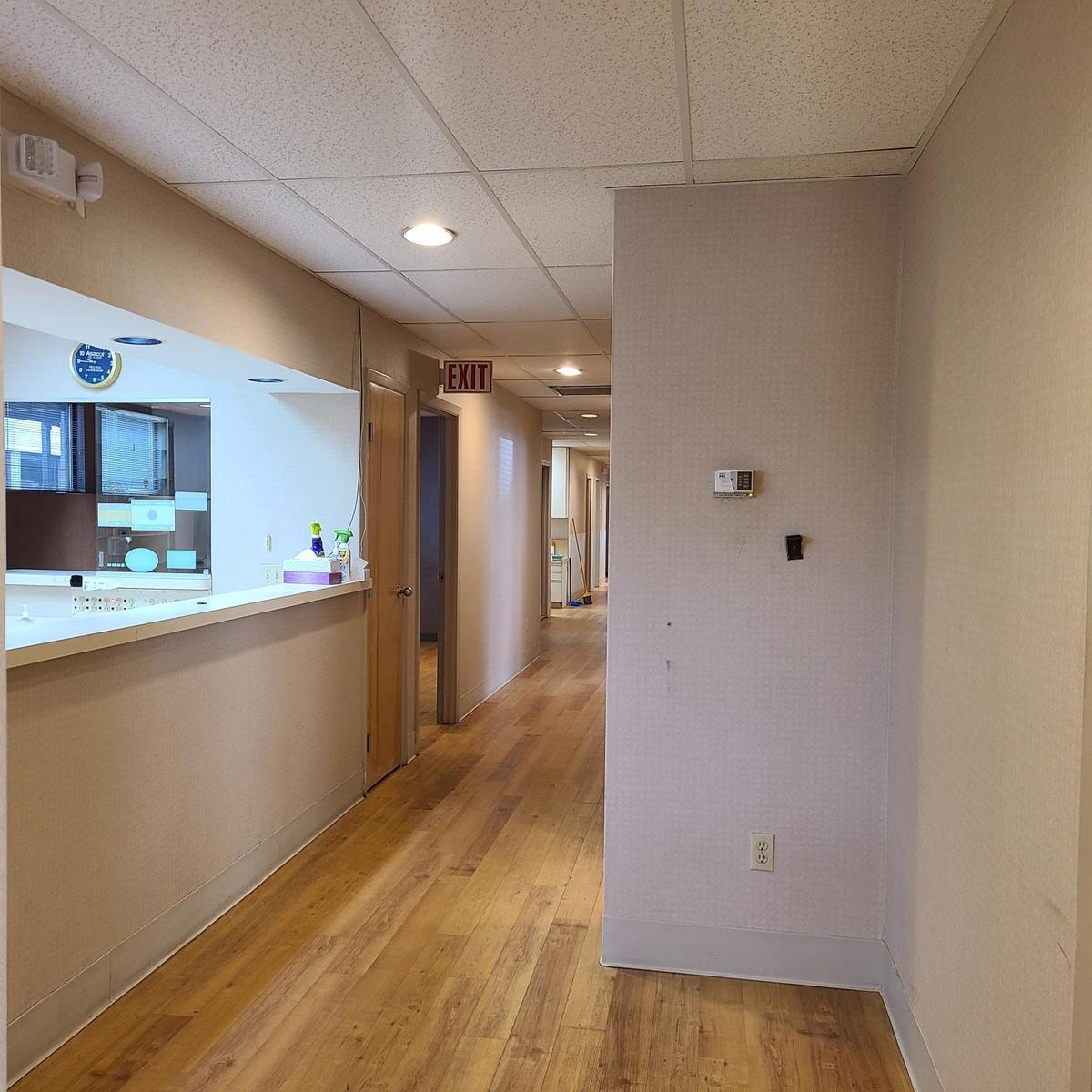 Hall with baseboards, light wood-style flooring, and a paneled ceiling