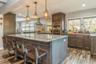 Kitchen featuring light stone countertops, stainless steel double oven, hanging light fixtures, and a kitchen island