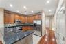 Kitchen featuring wood cabinetry, stainless steel appliances, dark stone countertops, a mosaic tile backsplash, and recessed lighting