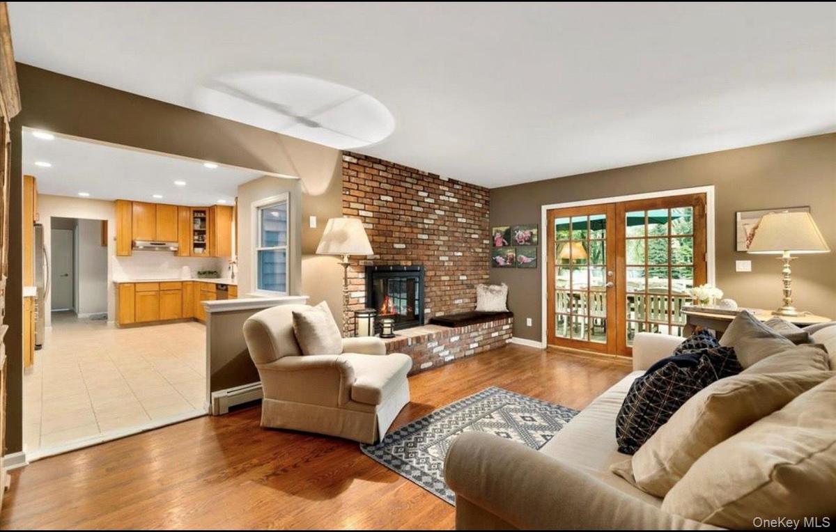 Living room with light wood-type flooring, a fireplace, recessed lighting, and a baseboard heating unit