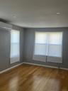 Empty room featuring a wealth of natural light, wood finished floors, and an AC wall unit