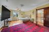 Bedroom featuring wood finished floors, crown molding, a baseboard radiator, and a ceiling fan