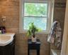 Bathroom featuring full-height stone-finish wall tile, a single-hung window with privacy film, a dark wood-finish vanity with a white countertop, and 