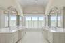 Bathroom featuring a chandelier, two vanities, and high vaulted ceiling