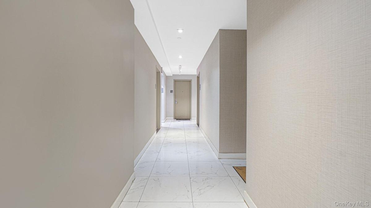 Hallway featuring light marble finish floors and recessed lighting