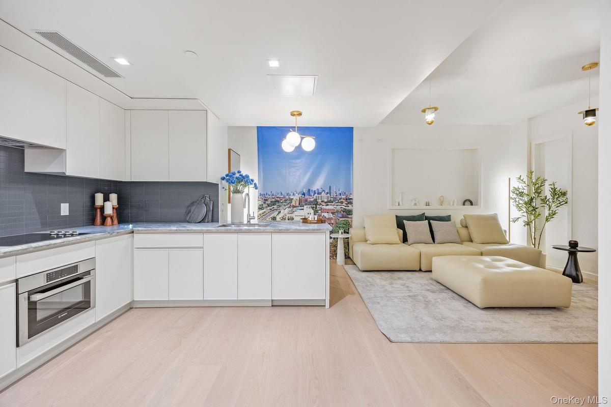 Kitchen with modern cabinets, stainless steel oven, white cabinets, and hanging light fixtures