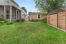 Expansive grassy lawn with a screened porch, a paved patio area, and a separate storage shed featuring wood-finish siding and a metal roof