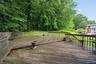 A spacious, party-sized wood deck perfect for outdoor entertaining, stepping out into a quiet, private backyard framed by lush, mature trees in Valley