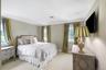 Elegant primary bedroom featuring multiple windows with natural light, neutral wall finishes, and wall-mounted flat-screen television