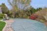 View of swimming pool with a patio, a covered pool, and view of scattered trees