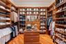 Custom closet system featuring wood-finish cabinetry, extensive shelving, built-in hanging rods, and a central island with integrated drawers