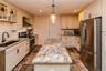 Kitchen featuring a center island with a stone surface, perimeter cabinetry with stone countertops, stainless steel appliances, a tile backsplash, and