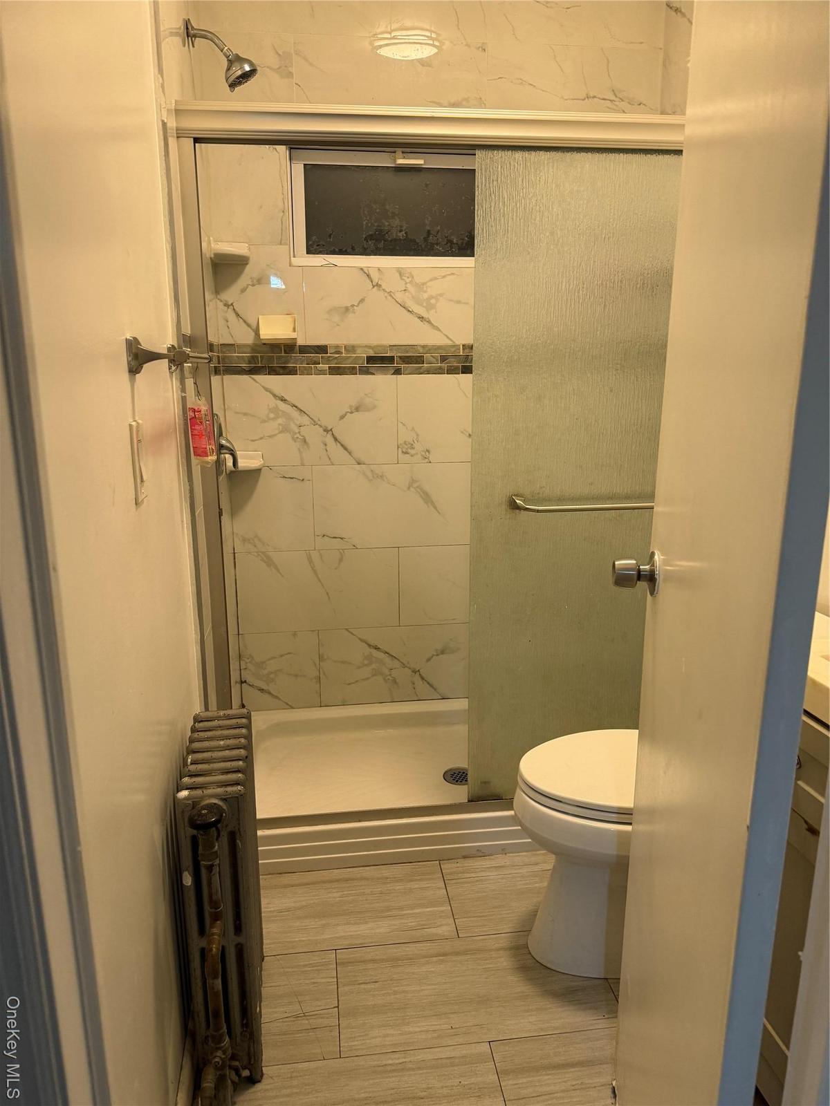 Full bathroom with radiator heating unit, a shower stall, and vanity