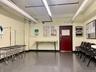 Community laundry room featuring multiple front-loading washing machines, durable flooring, and overhead fluorescent lighting