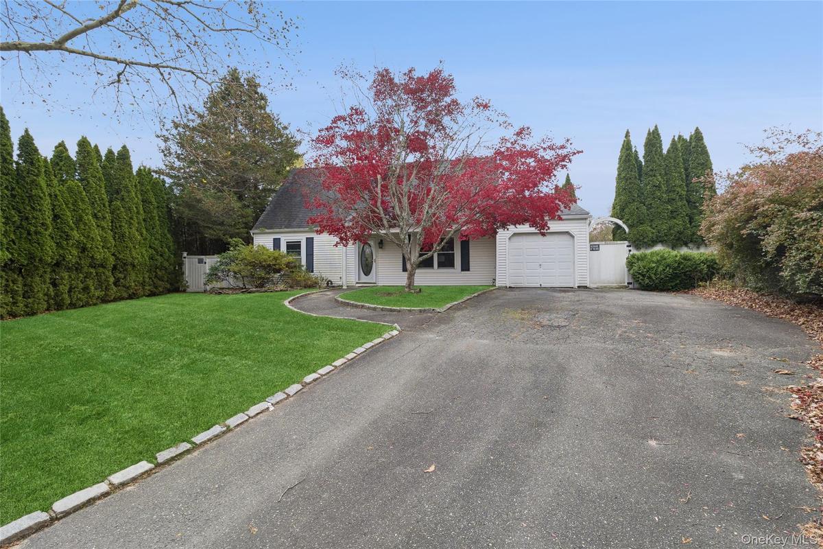 View of front facade featuring a front yard, driveway, and a garage