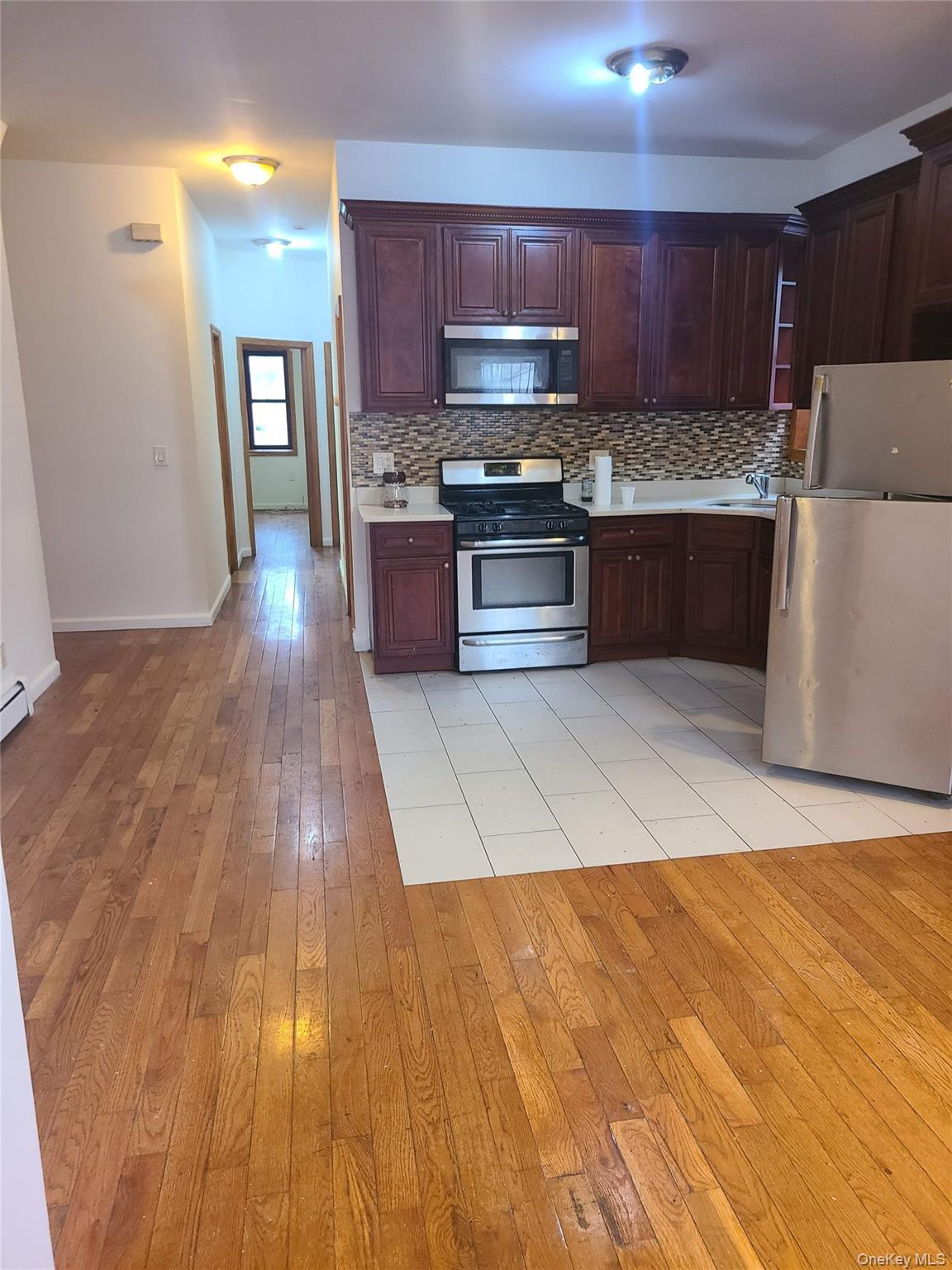Kitchen featuring light countertops, tasteful backsplash, appliances with stainless steel finishes, and light wood finished floors