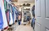 Walk-in closet featuring carpet flooring, white wire shelving, multiple hanging rods, and a paneled door