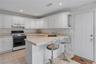U-shaped kitchen featuring white cabinetry, light-toned countertops, and a black range