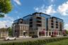 Contemporary multi-story building featuring extensive glazing, private balconies, and a brick facade