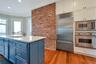 Kitchen featuring ornamental molding, brick wall, blue cabinets, sink, and built in appliances