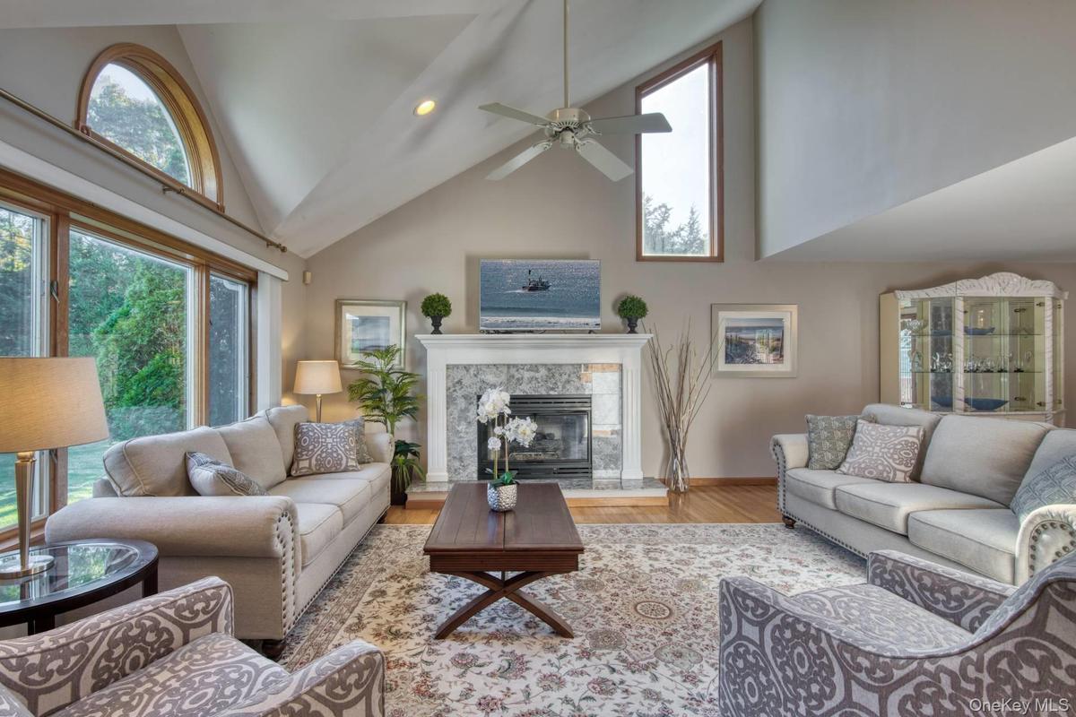 Living room with high vaulted ceiling, wood finished floors, a premium fireplace, recessed lighting, and a ceiling fan
