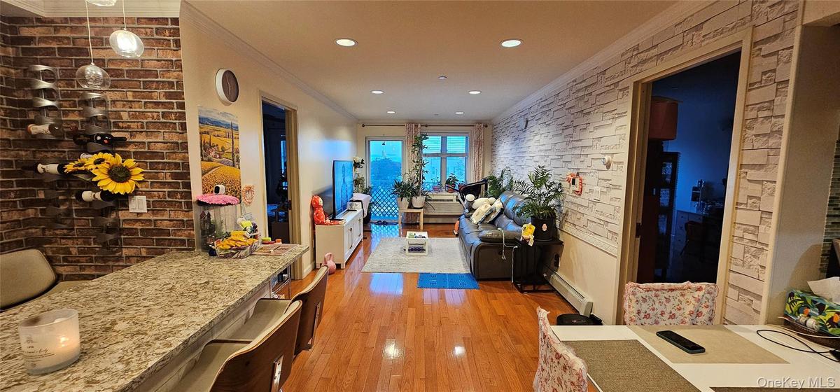 Corridor featuring crown molding, brick wall, light wood-style floors, a baseboard radiator, and recessed lighting