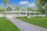 Ranch-style home with a chimney, an attached garage, roof with shingles, and asphalt driveway