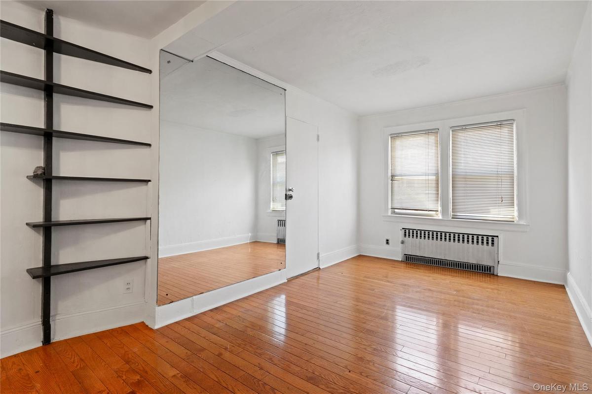Unfurnished bedroom featuring light wood finished floors and radiator heating unit