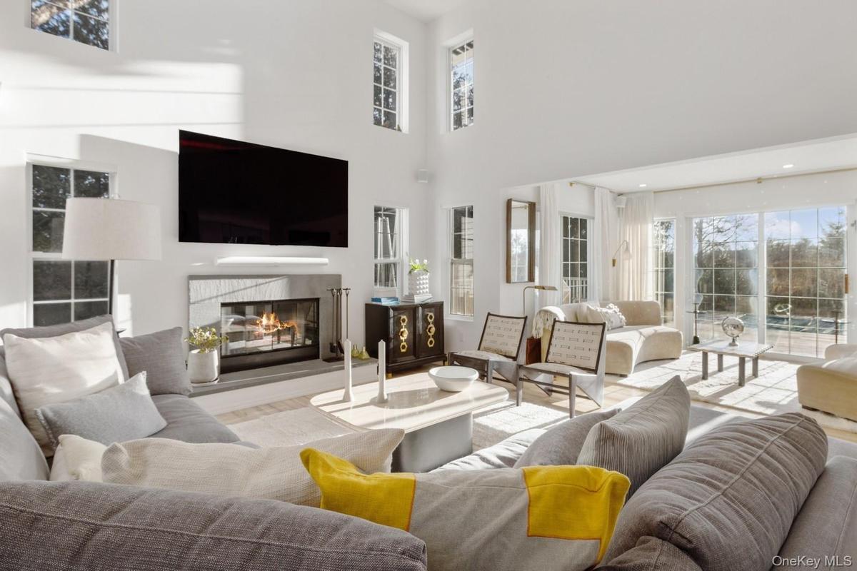 Living area with plenty of natural light, a glass covered fireplace, a high ceiling, and wood finished floors