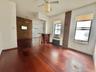 Unfurnished living room with radiator heating unit, wood finished floors, a ceiling fan, cooling unit, and brick wall