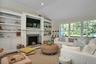 Living room featuring vaulted ceiling, built in shelves, a fireplace with raised hearth, and wood finished floors