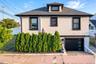 Two-story residence featuring a white stucco exterior and dark window trim