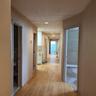 Hall featuring baseboards, light wood-style flooring, and a paneled ceiling