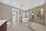 Freestanding soaking tub, glass-enclosed shower, wall-mounted showerhead, and matte black fixtures