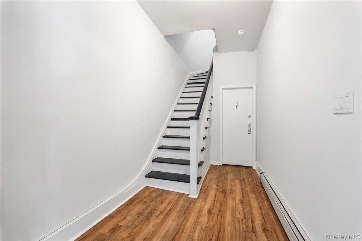 Staircase featuring a baseboard radiator and wood finished floors