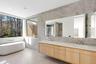 Full bathroom with tile walls, a freestanding bath, double vanity, a stall shower, and light tile patterned floors