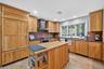 Kitchen featuring stone tile floors, wall chimney range hood, dishwasher, oven, and recessed lighting