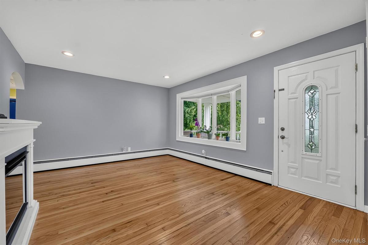 Sun-filled living room featuring beautifully refinished hardwood floors and a lovely bay window.