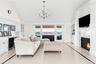 Living room featuring built in features, a premium fireplace, lofted ceiling, beverage cooler, and a chandelier