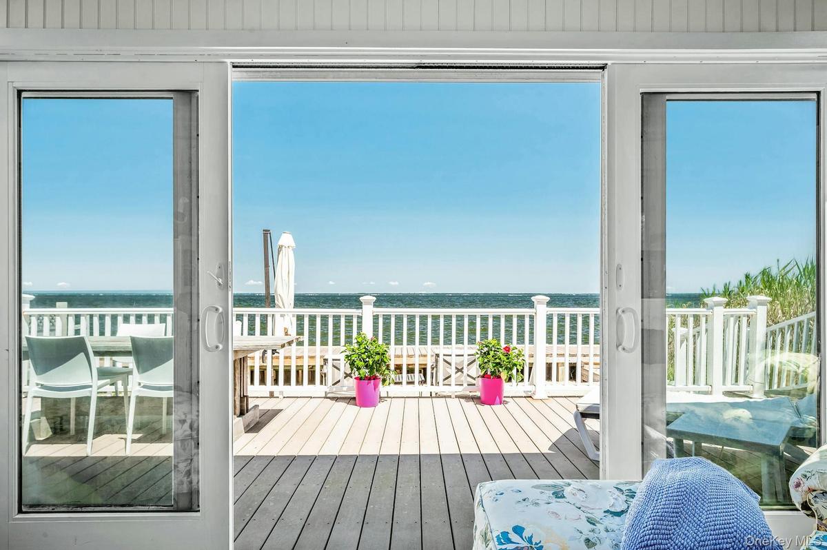 Sliding glass doors opening onto an expansive exterior deck with bay frontage