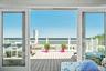 Sliding glass doors opening onto an expansive exterior deck with bay frontage