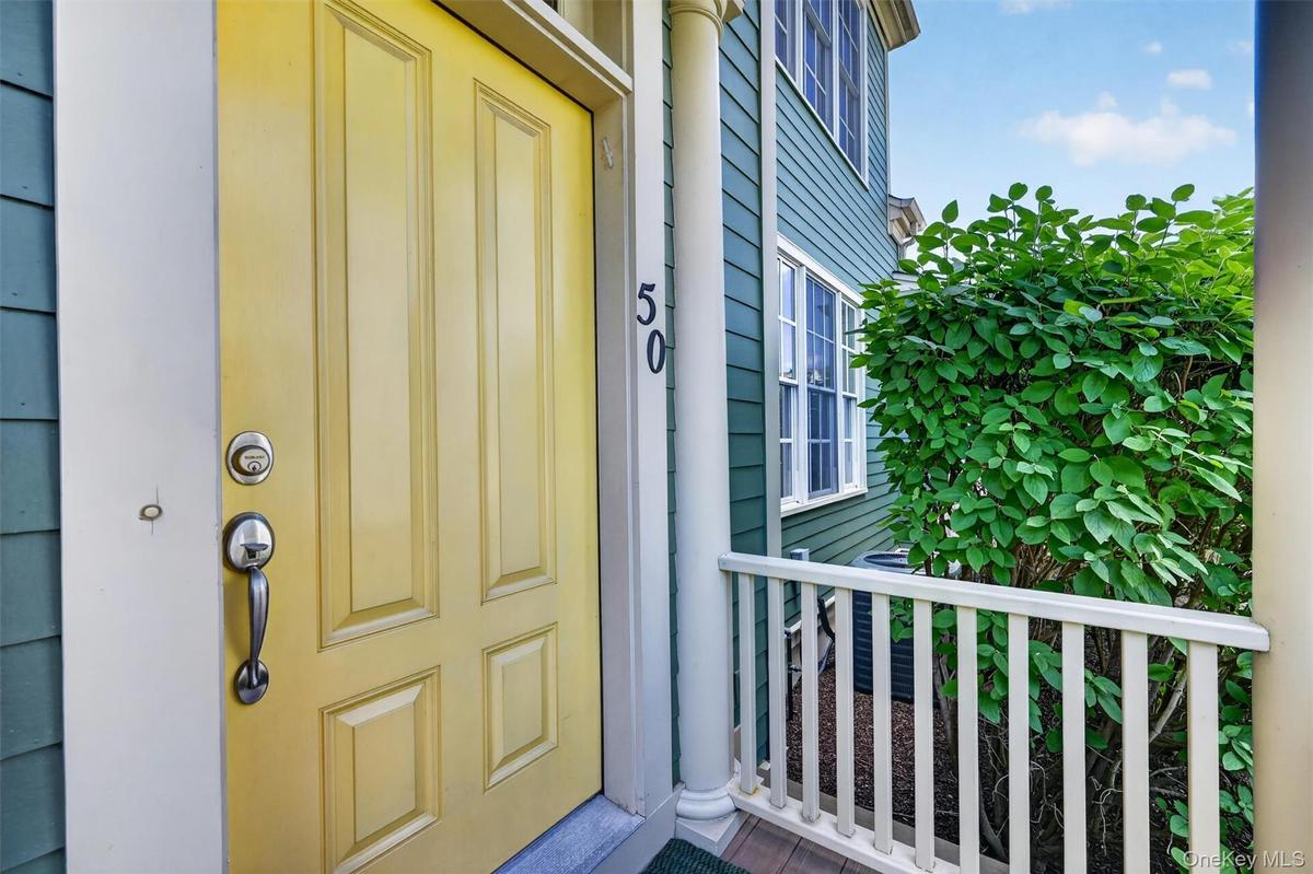 A cheerful yellow front door and covered porch create a warm first impression before stepping inside.