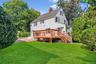 Back of property featuring a yard, a chimney, roof with shingles, and a wooden deck