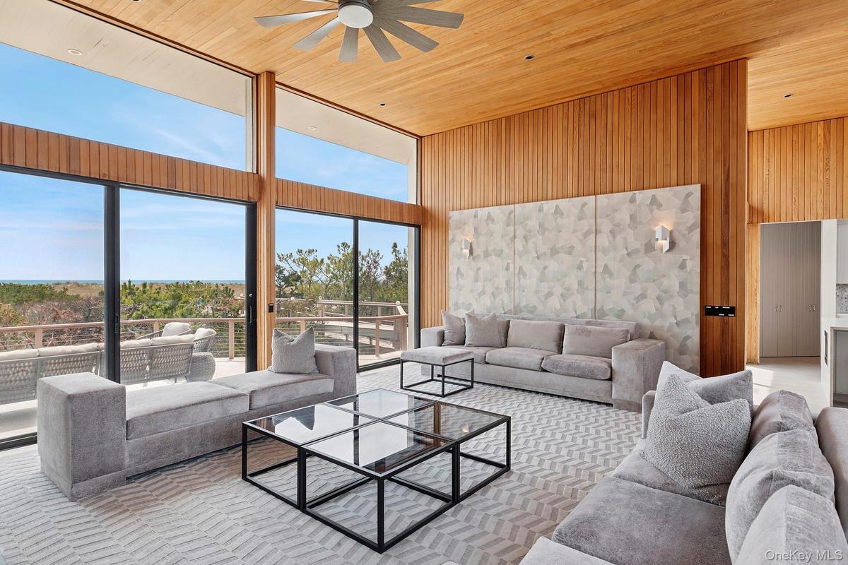 Living room featuring wood walls, wood ceiling, a high ceiling, and a ceiling fan