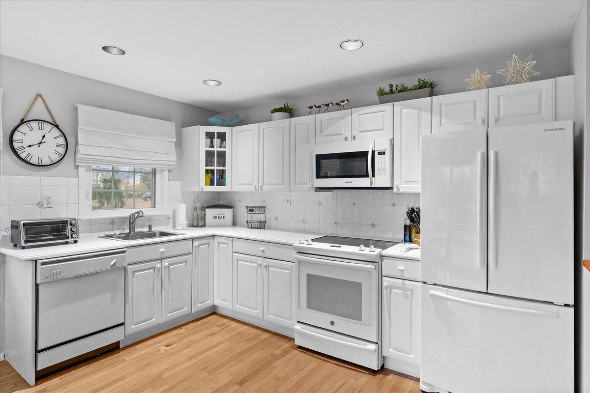 Kitchen featuring a sink, a toaster, light wood-style floors, white appliances, and light countertops