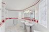 Bathroom with tile patterned floors, double sink, and tile walls